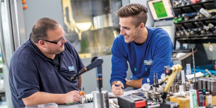 Two production workers are talking while working