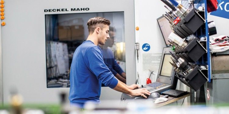 Koziol worker stands in front of the computer in the production hall.