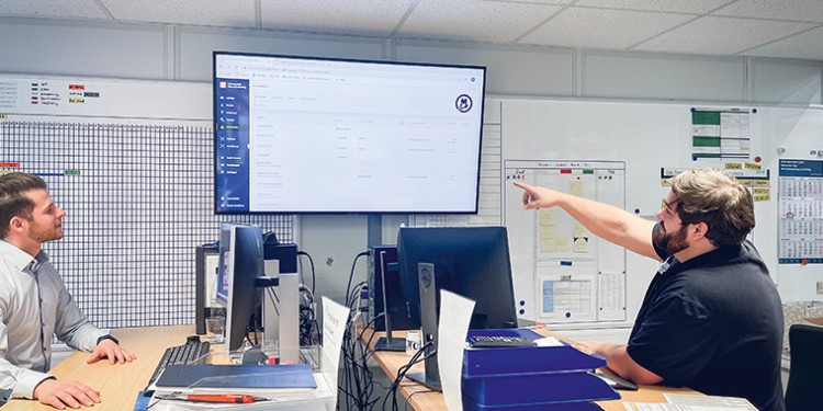 two employees sit in front of a monitor