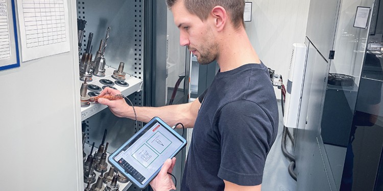 employee stands with tablet in front of a tool cabinet